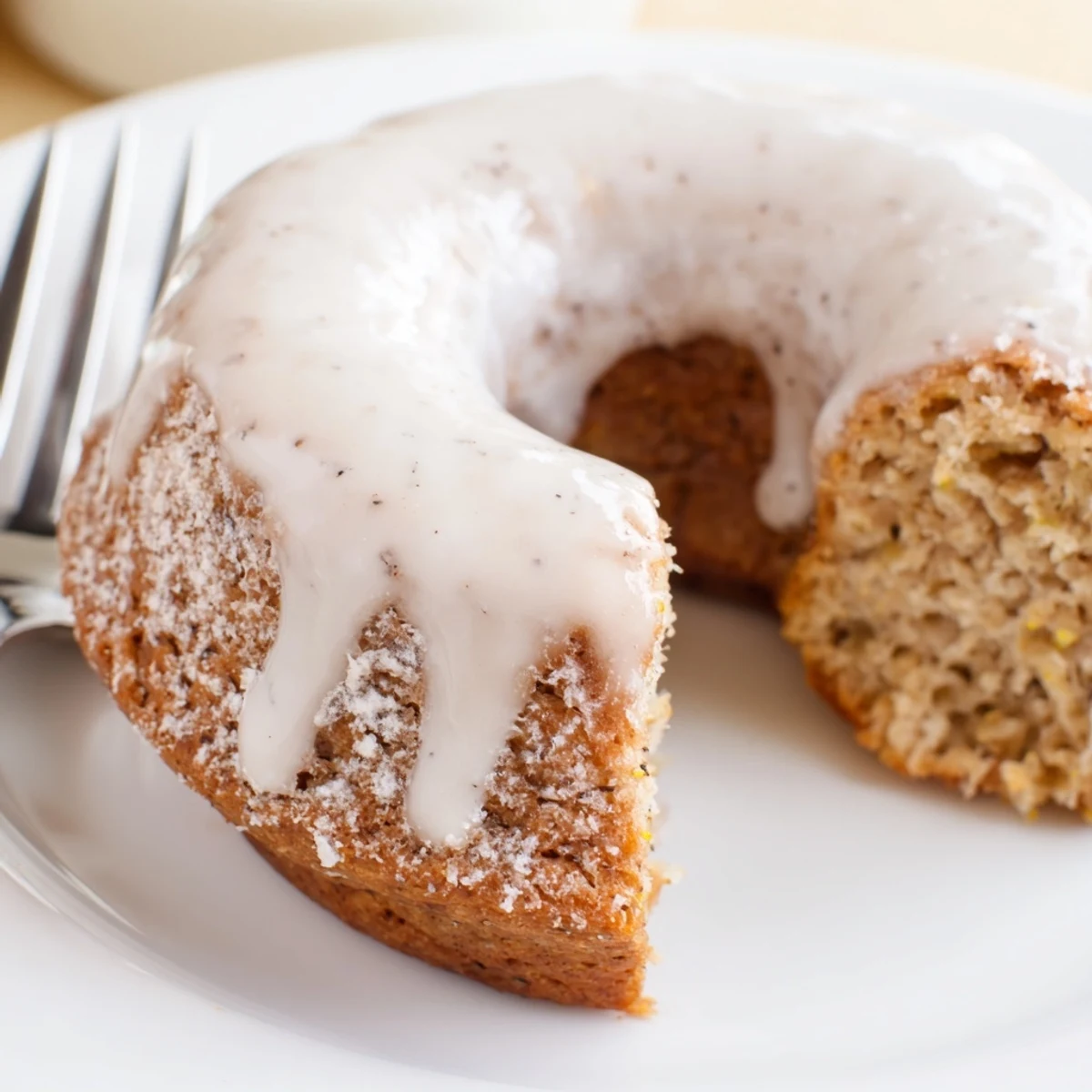 Golden banana bread donuts topped with sweet white glaze on a wire rack
