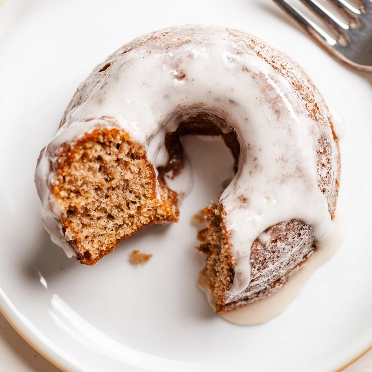 Moist baked banana bread donuts with powdered sugar coating cooling on baking sheet