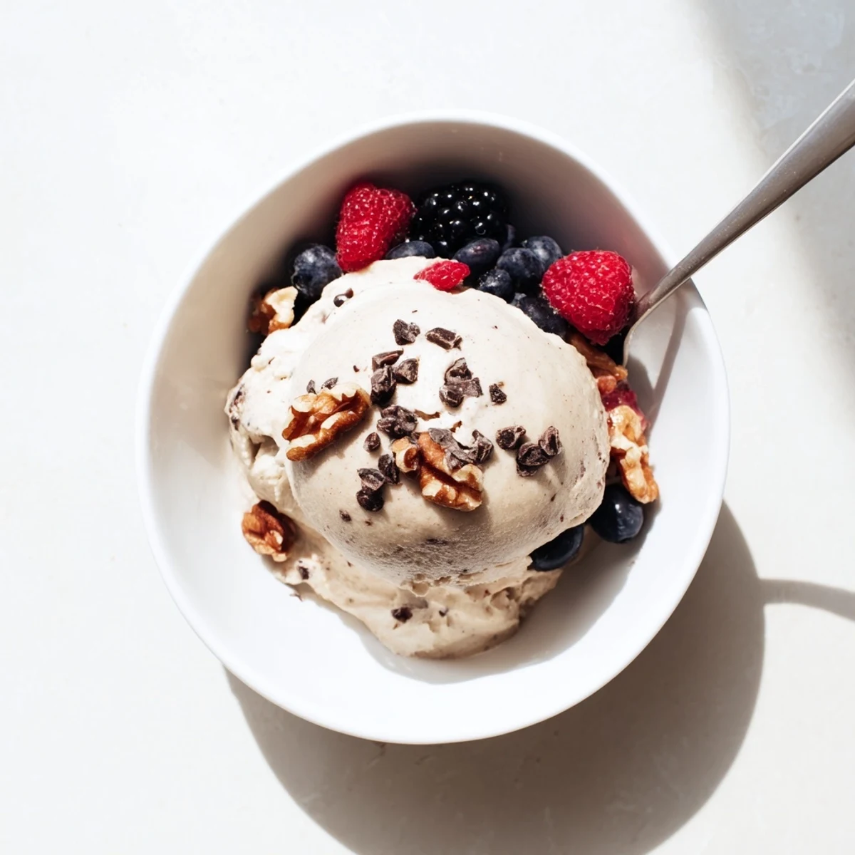 Creamy banana nice cream bowl topped with fresh berries and dark chocolate chips