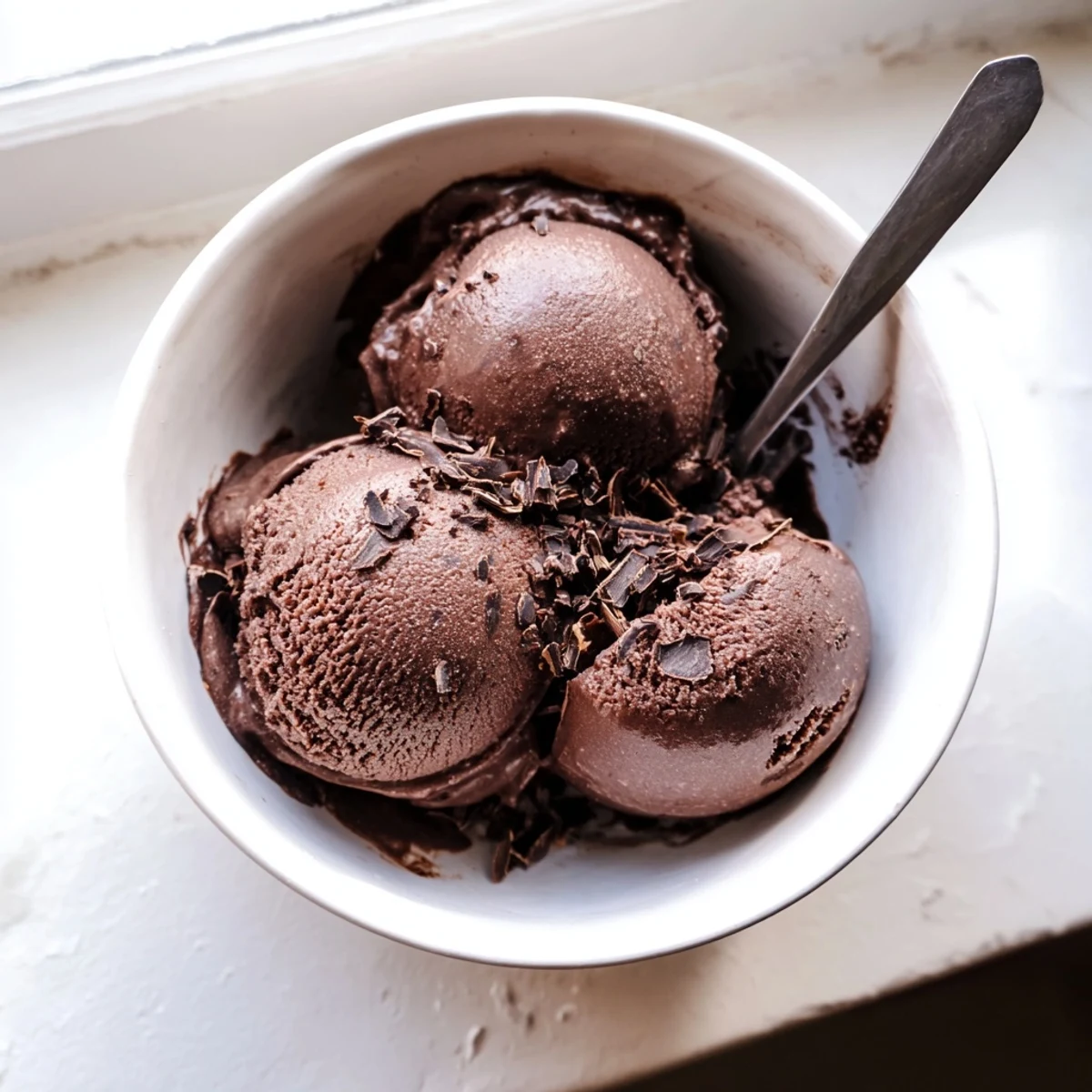 Creamy chocolate sourdough ice cream scooped into a bowl with melted dark chocolate ribbons swirled throughout