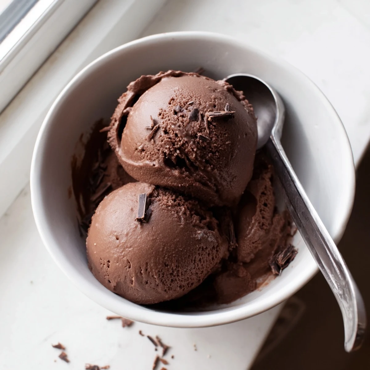 Rich chocolate sourdough ice cream served in a vintage glass dish topped with fresh raspberries and sea salt