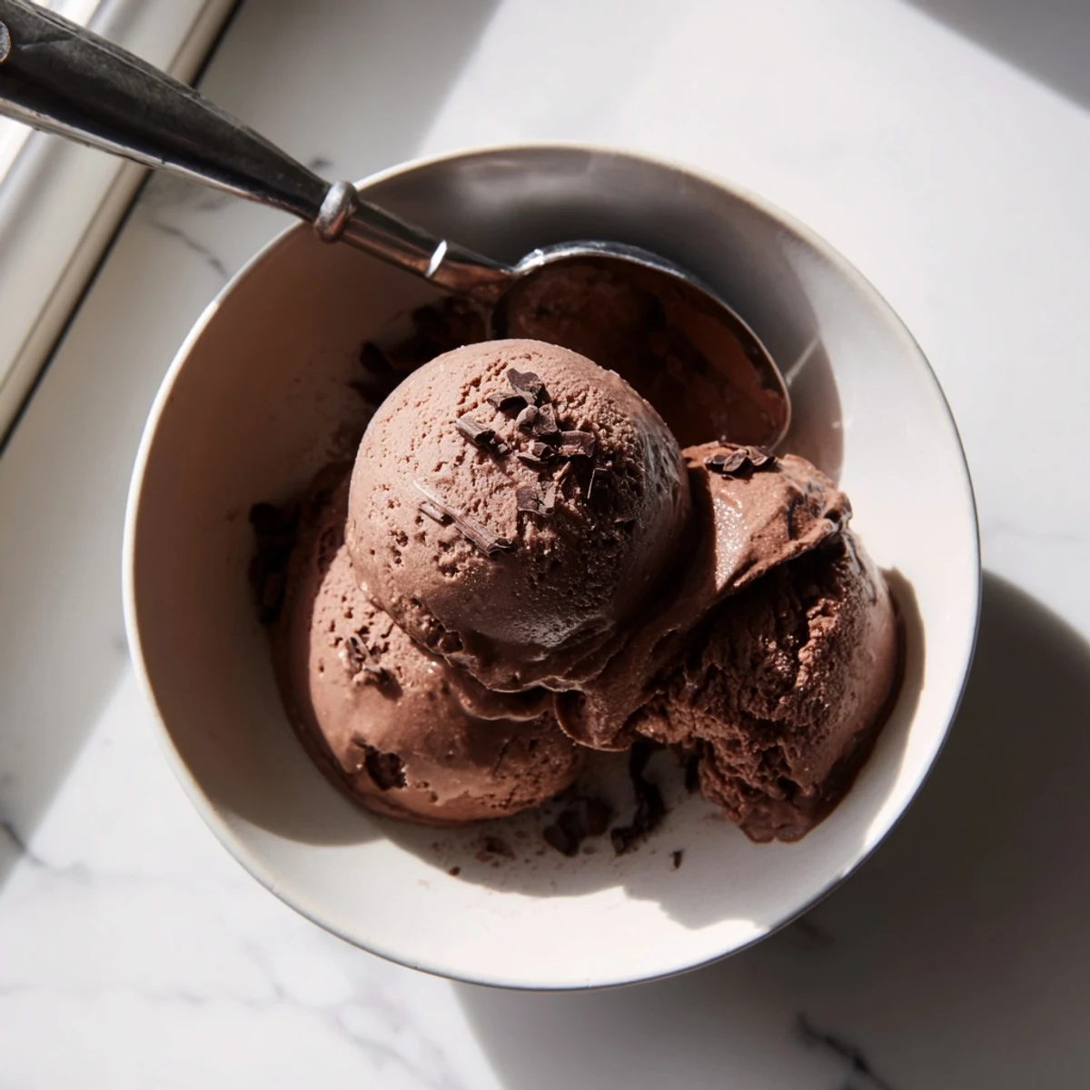 Velvety chocolate sourdough ice cream showing its smooth fudge-like texture on a wooden dessert spoon