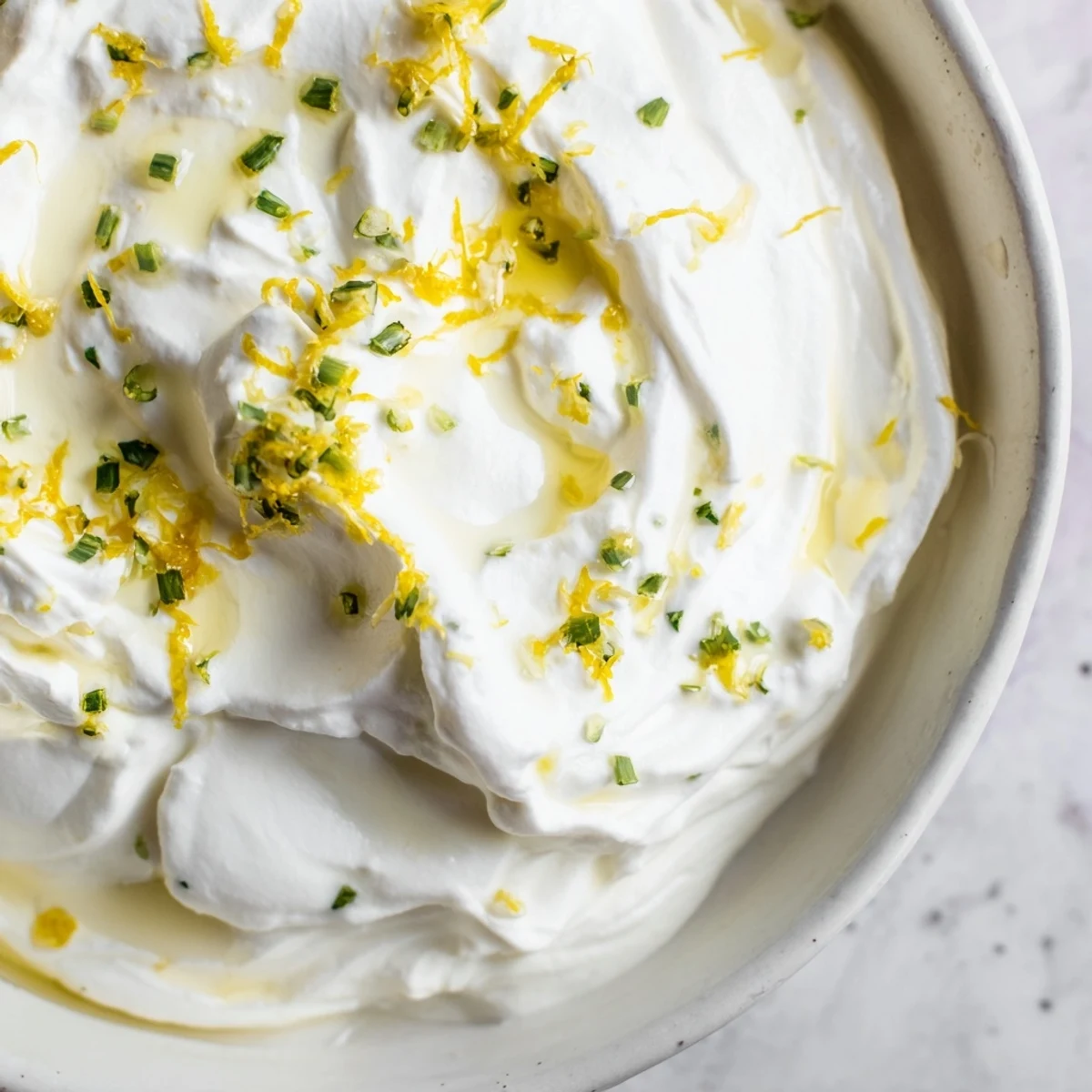 Light and airy whipped ricotta bowl garnished with basil, red pepper flakes, and extra virgin olive oil