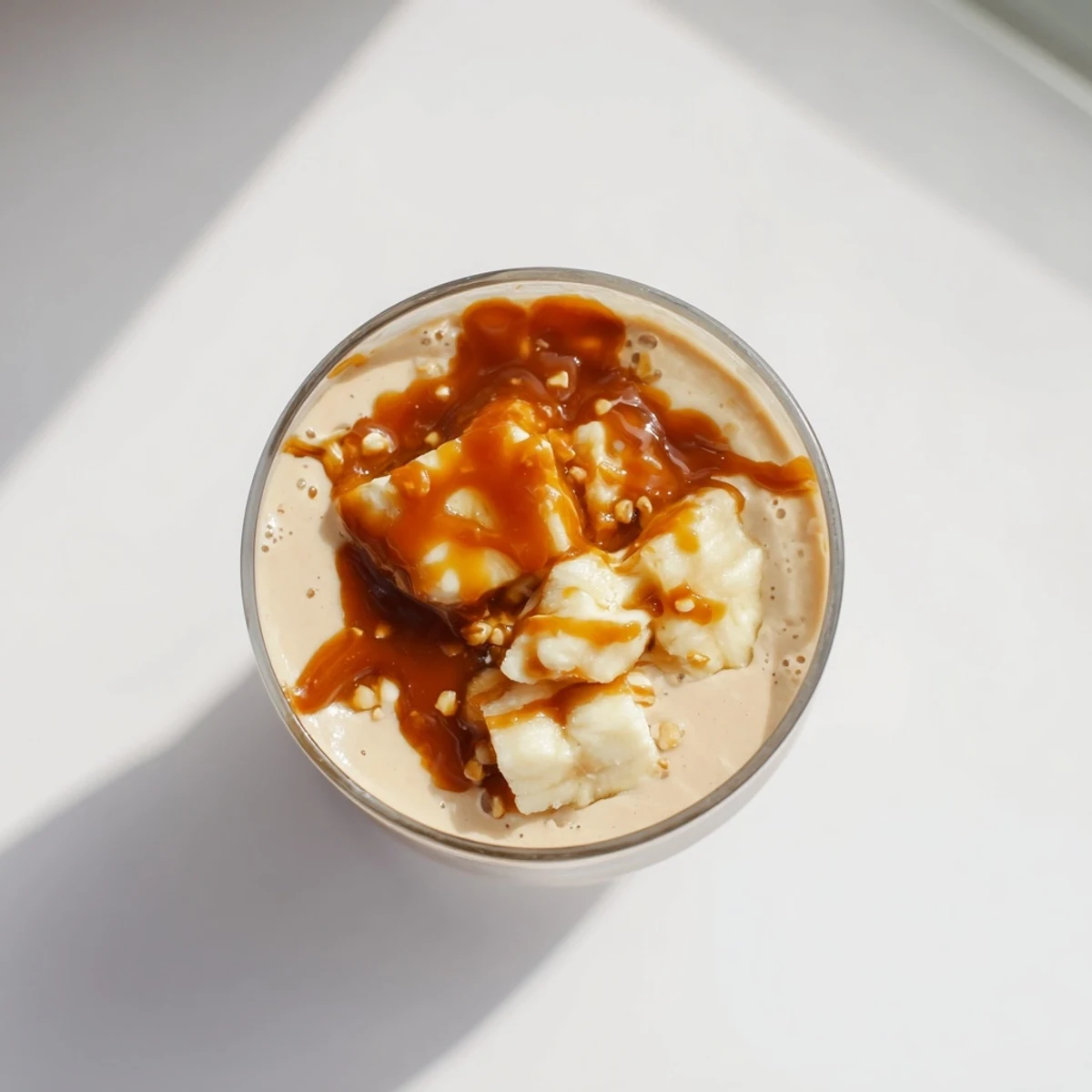 Creamy salted caramel protein smoothie poured into a glass with caramel drizzle running down the sides