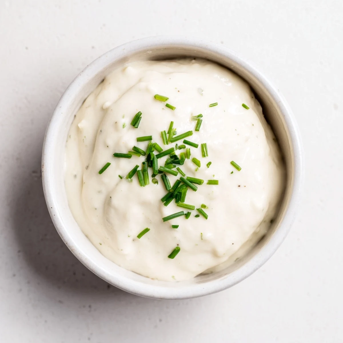 Creamy homemade horseradish sauce with a smooth white texture and fresh herb garnish