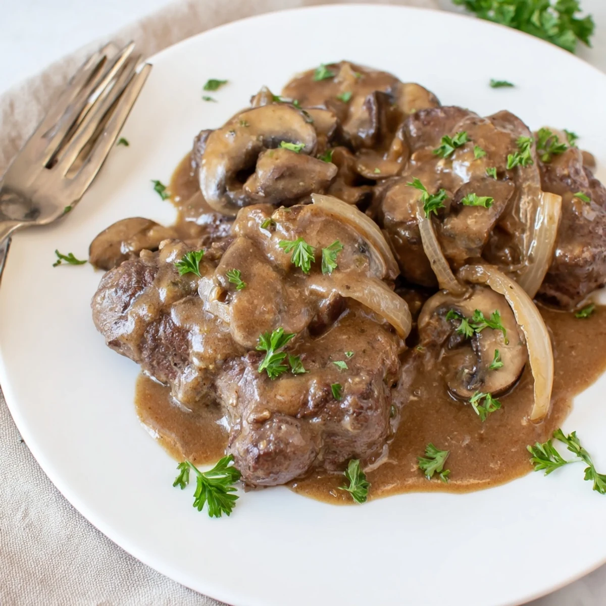 Fork-tender smothered cube steak plated with thick mushroom and onion sauce