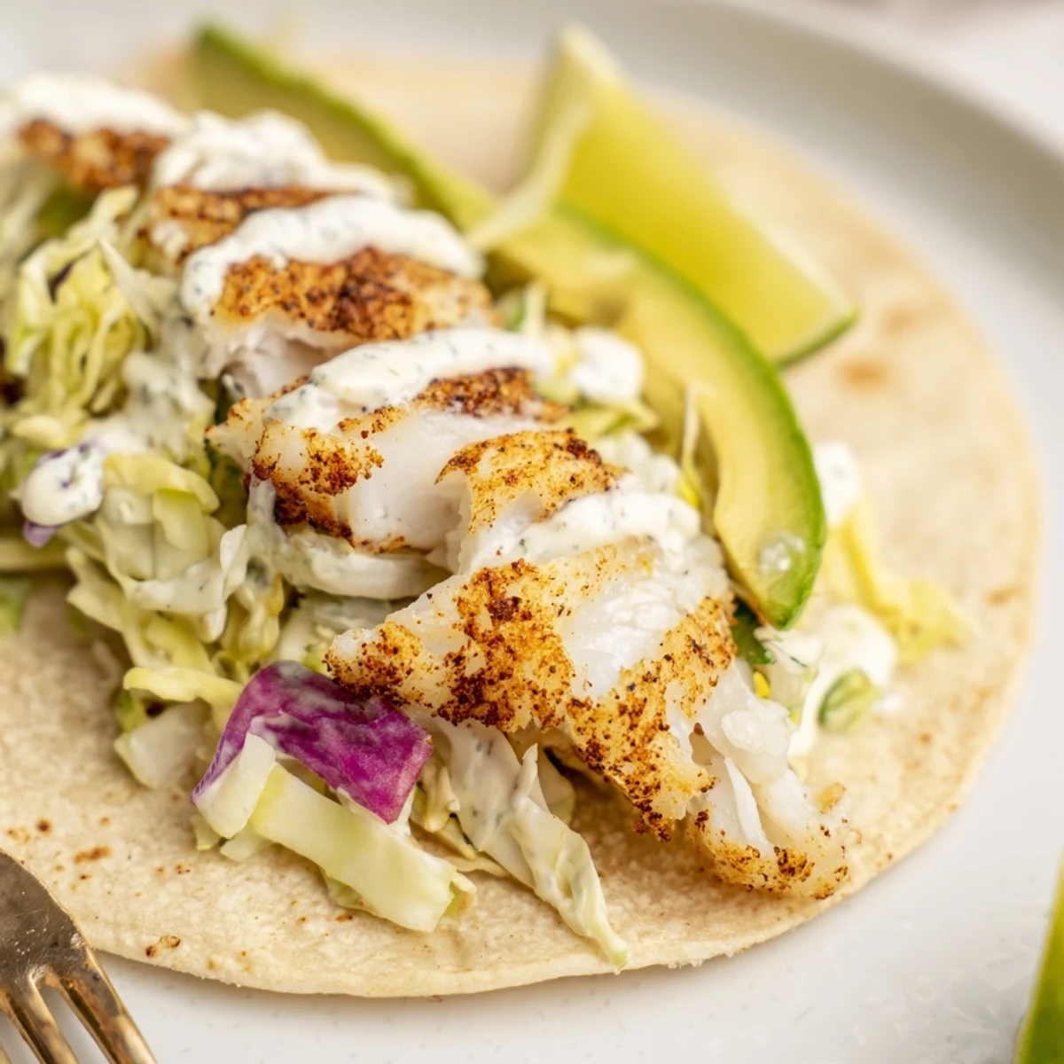 Baked Cod Fish Tacos with Creamy Cilantro Lime Sauce served with zesty lime wedges.