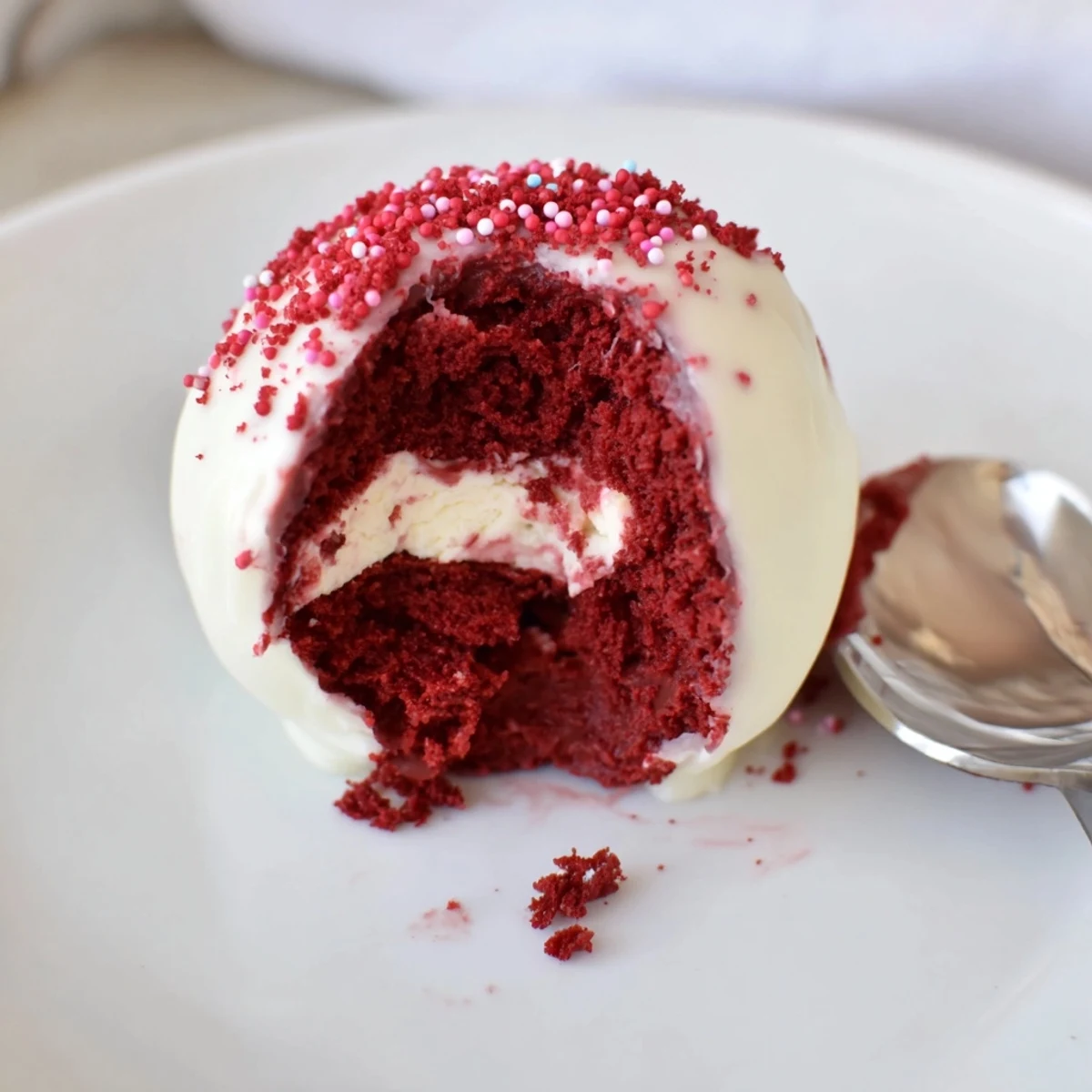 Red Velvet Cheesecake Balls displayed on parchment, glossy chocolate coating and crumbs.  