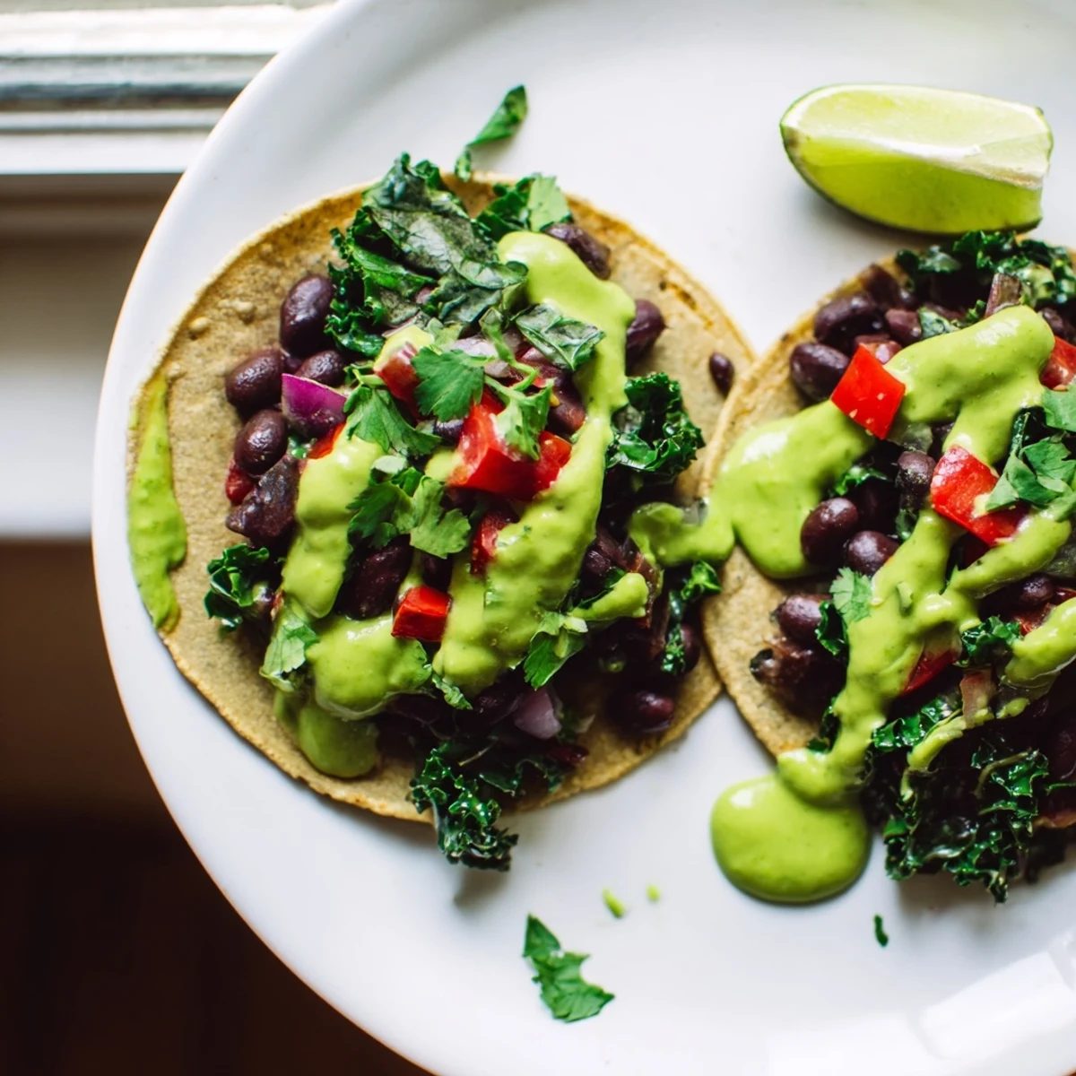 Warm corn tortillas filled with smoky black bean kale tacos and herby avocado sauce