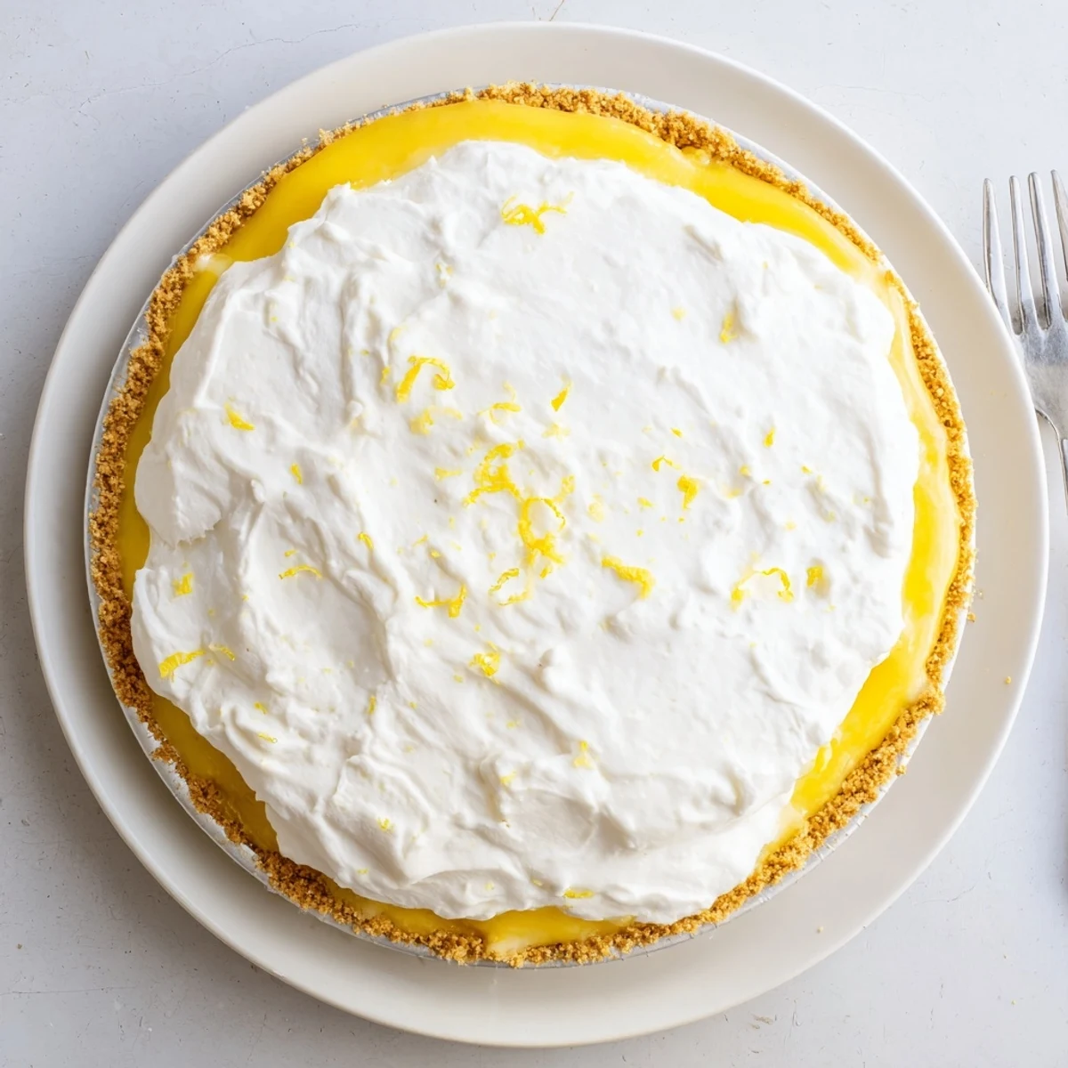 Creamy real lemon pie sliced and topped with fluffy whipped cream