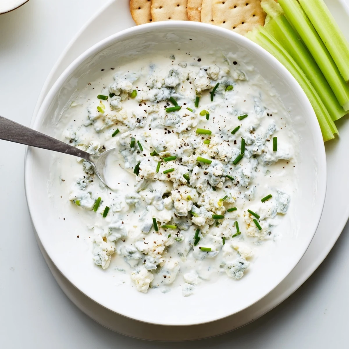 Creamy blue cheese dip served in a bowl with fresh celery sticks and crackers