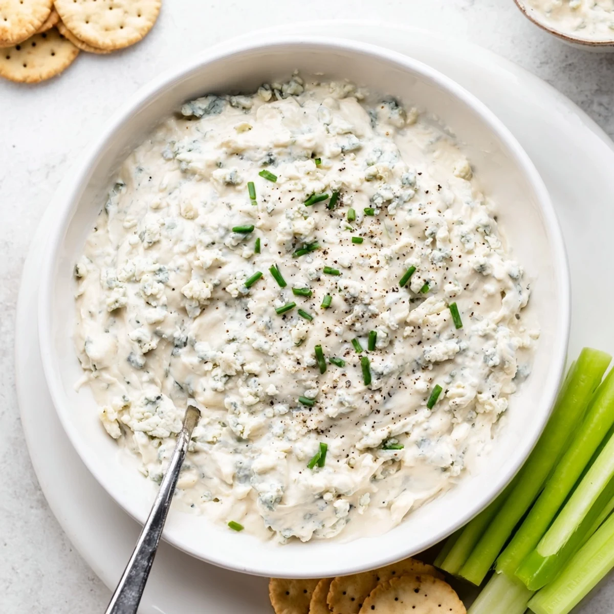 Rich blue cheese dip in a rustic bowl surrounded by crisp vegetables and wings