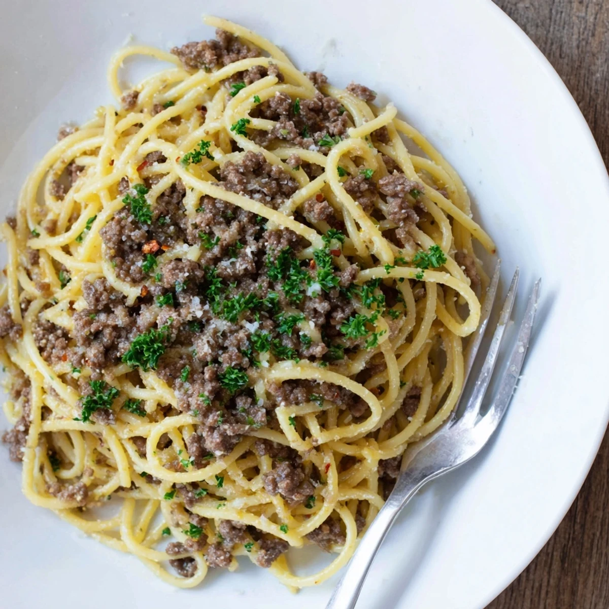Steaming bowl of garlic butter pasta with ground beef coated in rich sauce