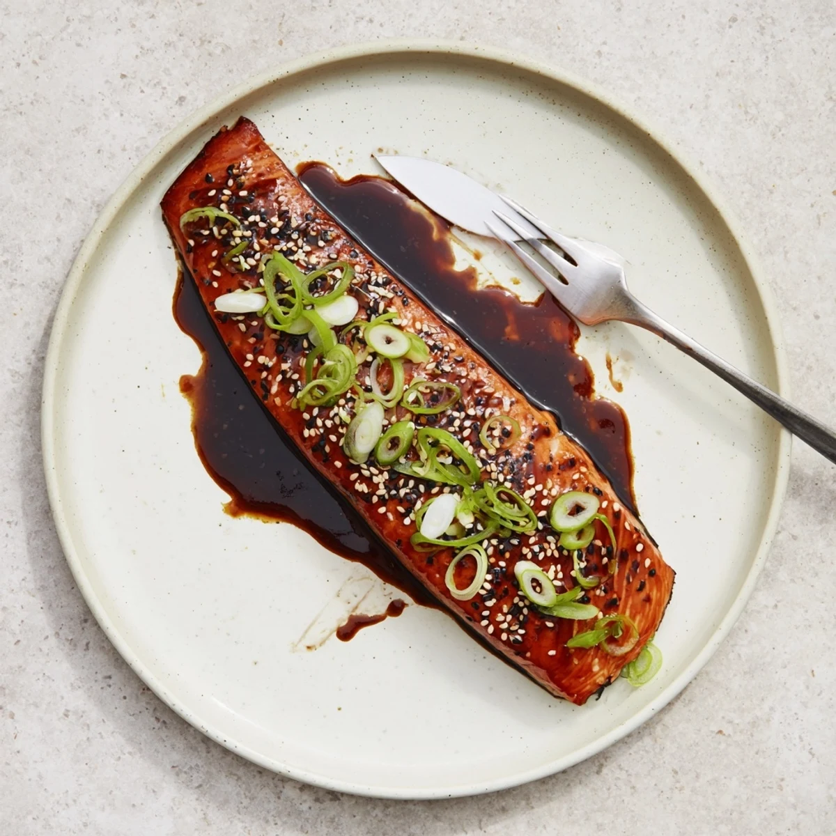 Caramelized gluten free teriyaki salmon fillets glistening with glossy sauce on a white plate
