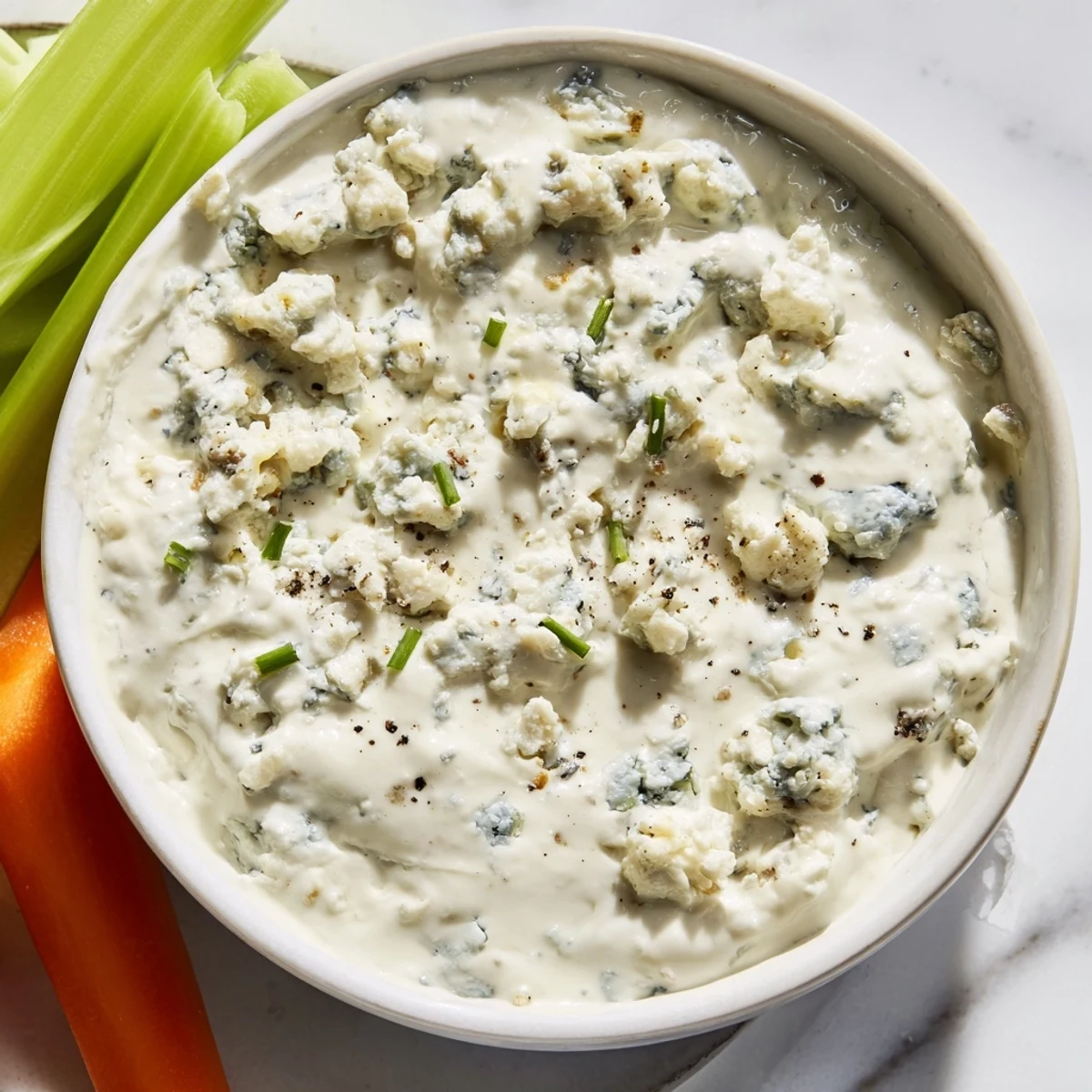 Creamy blue cheese dip served in a rustic bowl with crisp celery and carrot sticks