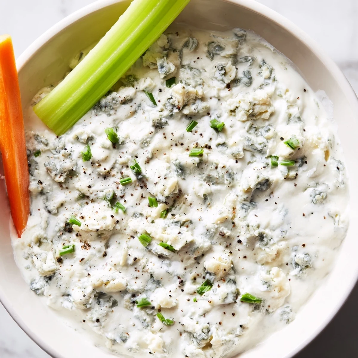 Thick blue cheese dip topped with fresh chives, ready for buffalo wings night