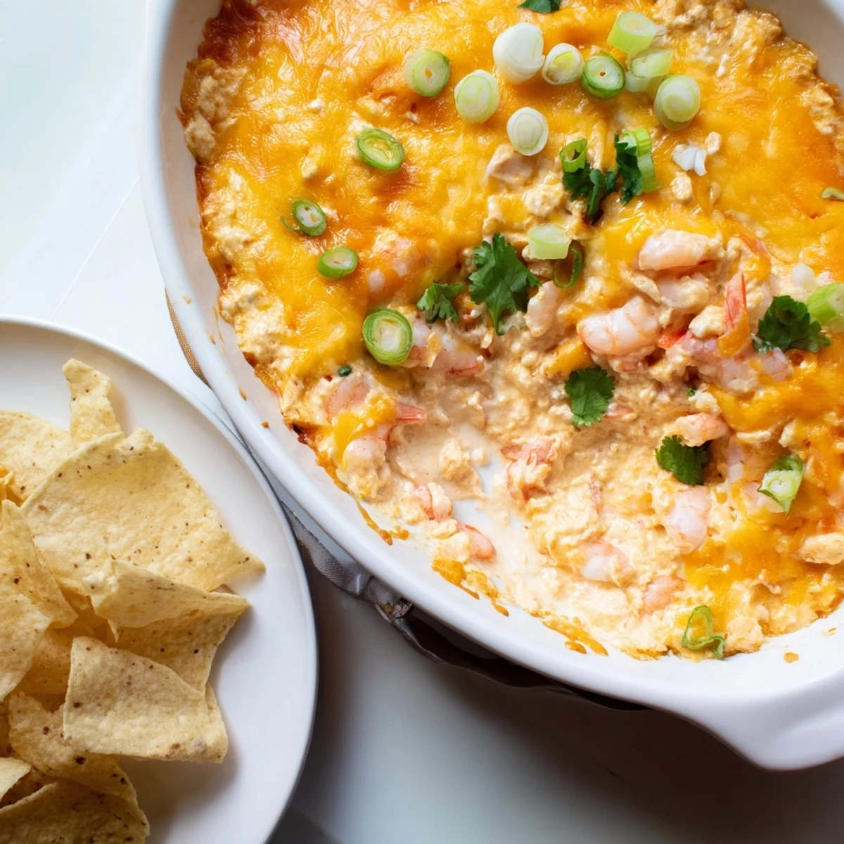 Warm extra cheesy bang bang shrimp dip served with crispy tortilla chips