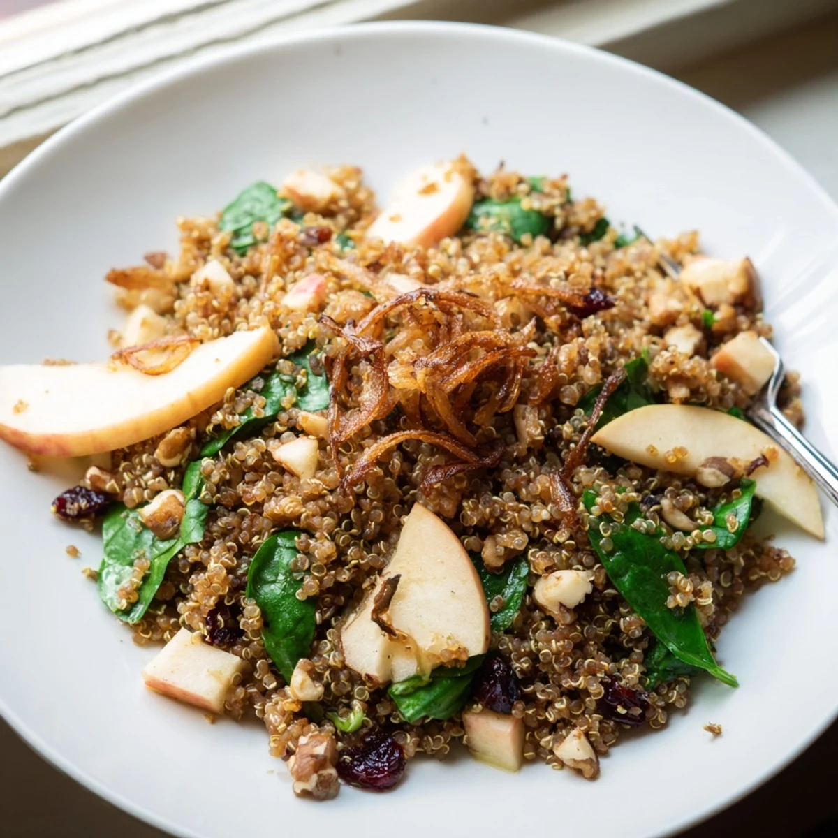 Honey Mustard Quinoa Apple Salad topped with golden crispy shallots on a rustic wooden bowl