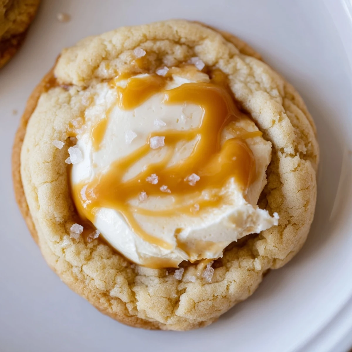 Soft caramel cheesecake cookies with golden caramel drizzle on a rustic baking sheet