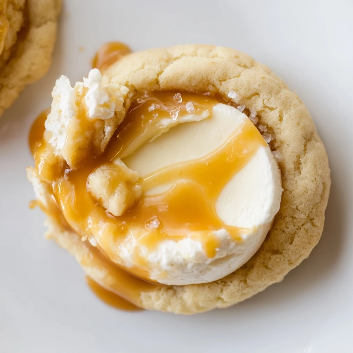 Warm caramel cheesecake cookies arranged on parchment with swirled caramel and golden edges