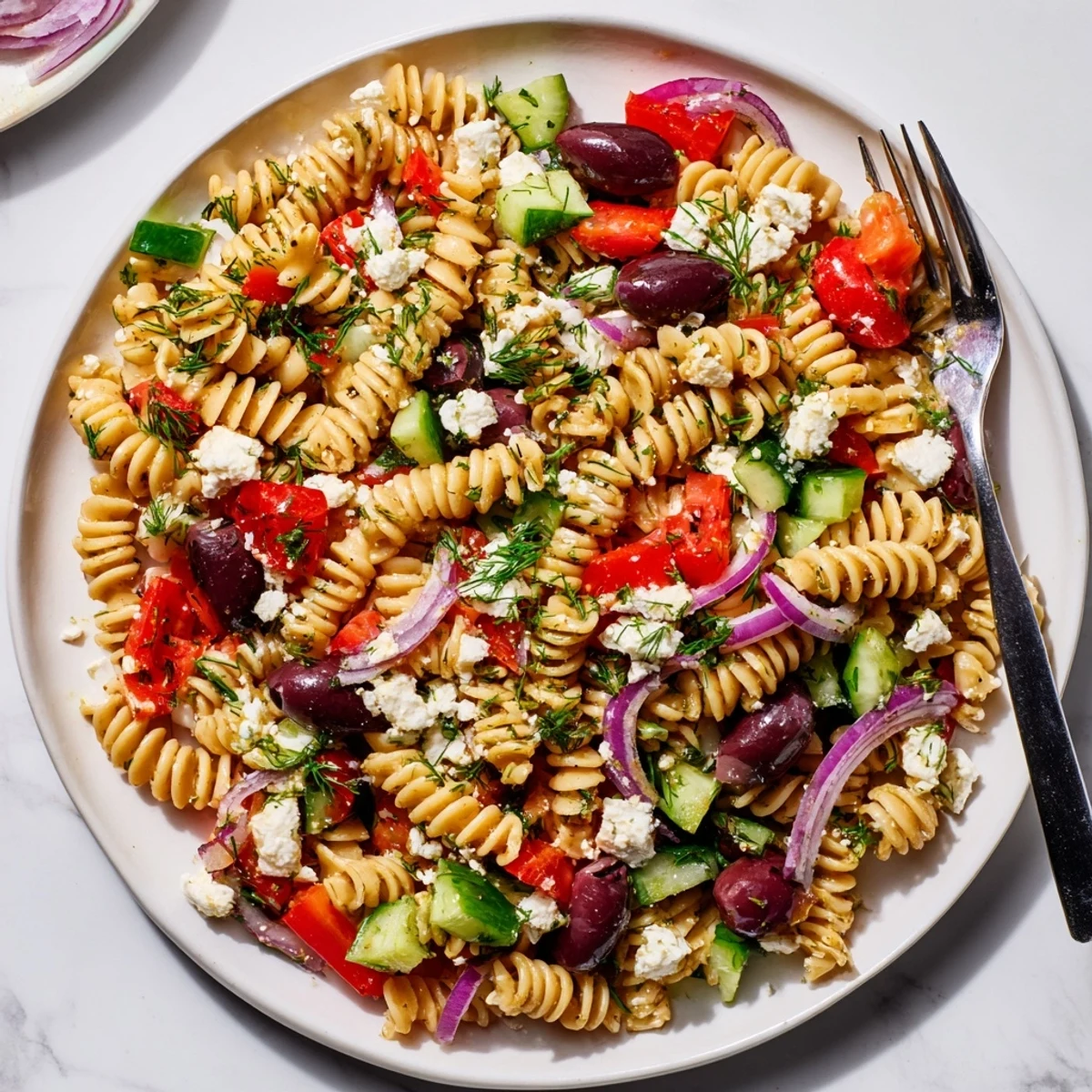 Creamy feta and Kalamata olives top this chilled Greek pasta salad on a rustic serving platter