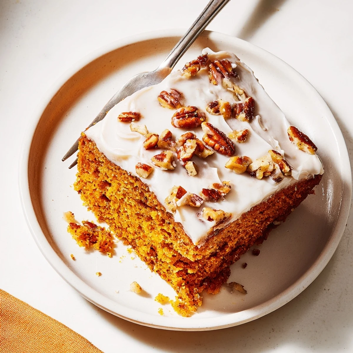Moist pumpkin pecan cake layered with rich cinnamon cream cheese frosting on an autumn table