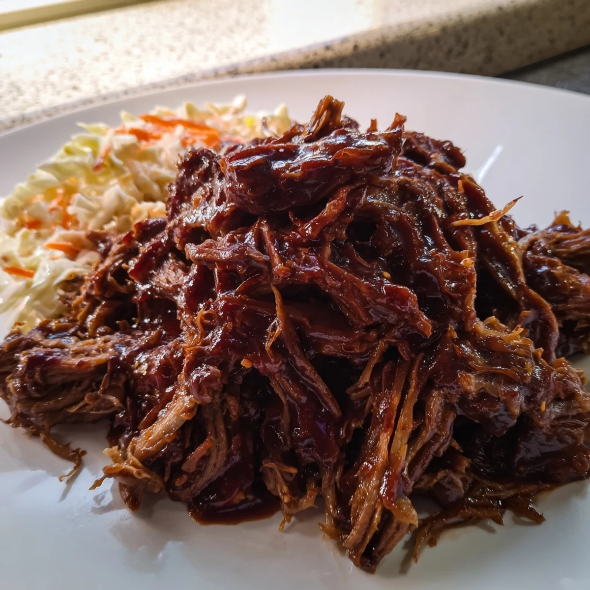 Savory slow cooker BBQ pulled beef draped in rich, glossy barbecue sauce ready for serving