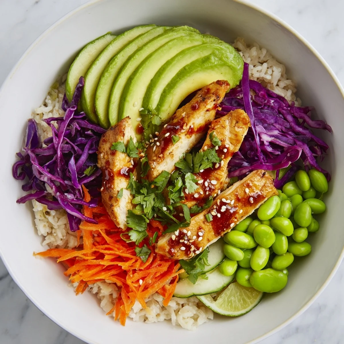 Golden marinated chicken strips nestled over brown rice with shredded cabbage carrots and creamy avocado slices