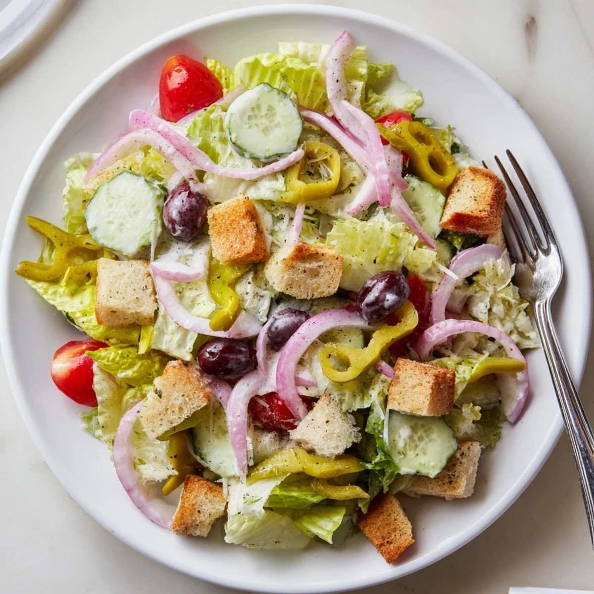 Fresh Olive Garden Salad topped with pepperoncini, black olives, and golden garlic croutons.