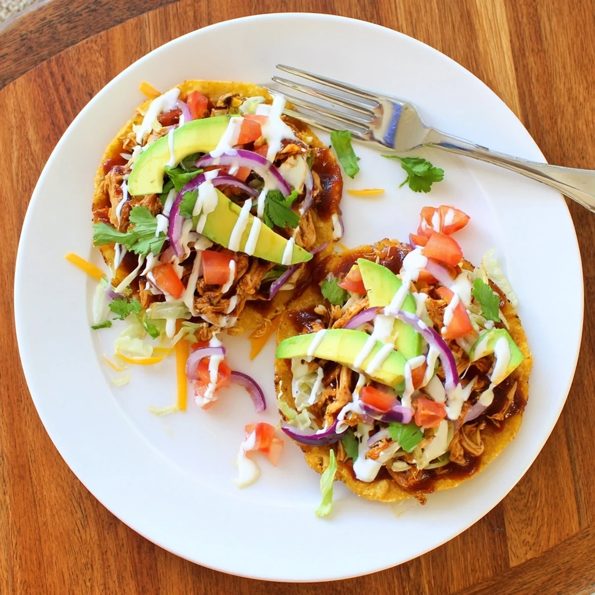 Golden tostada shells loaded with tender sweet smoky BBQ chicken, melted cheese, and vibrant cilantro garnish