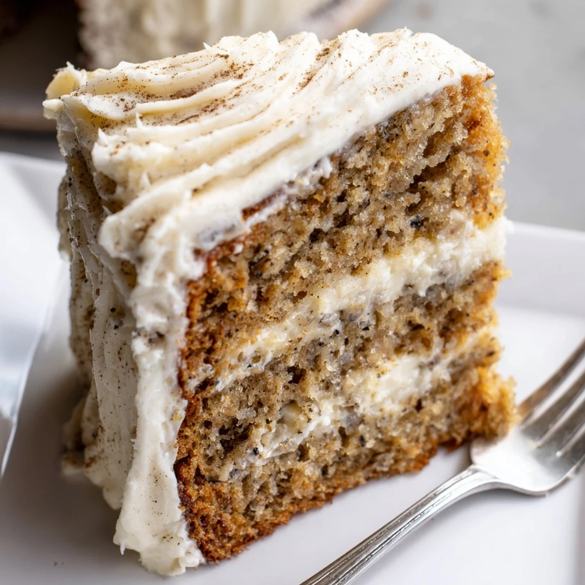 Rich brown butter banana cake layered with fluffy cream cheese frosting served on white parchment