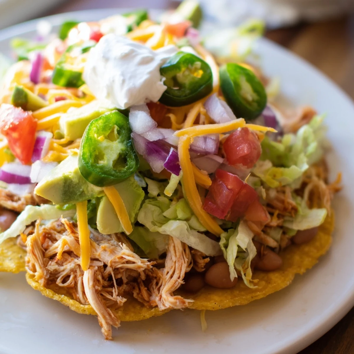 Golden crispy chicken tostadas piled with fresh lettuce, cheese, and creamy avocado.
