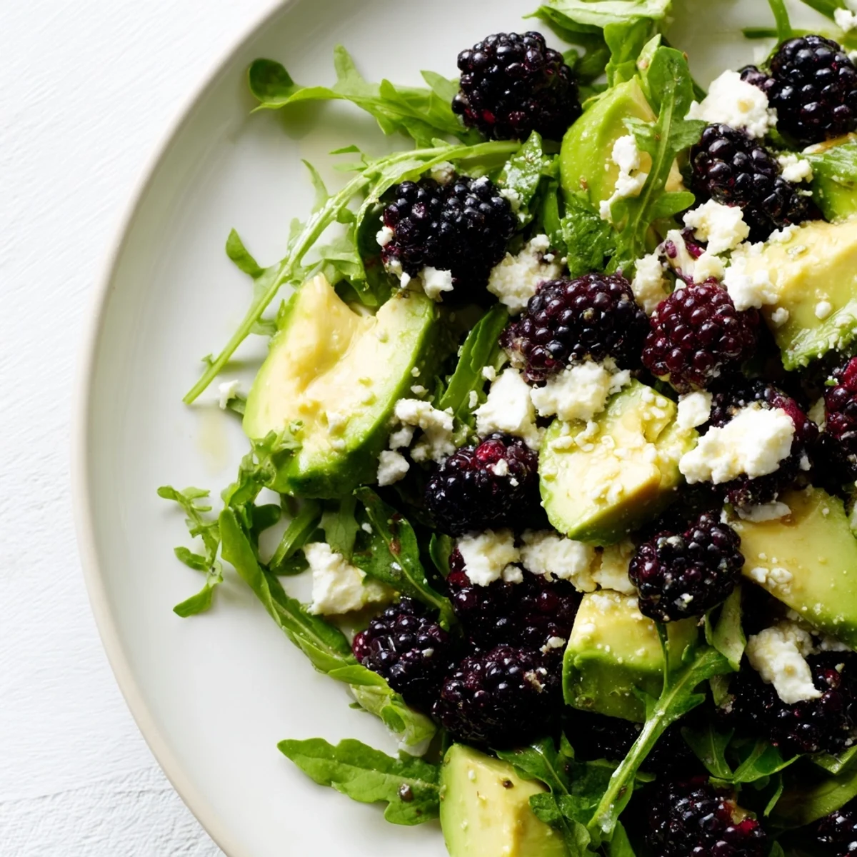 Close-up of blackberry avocado salad featuring ripe avocado, fresh berries, and peppery arugula lightly coated