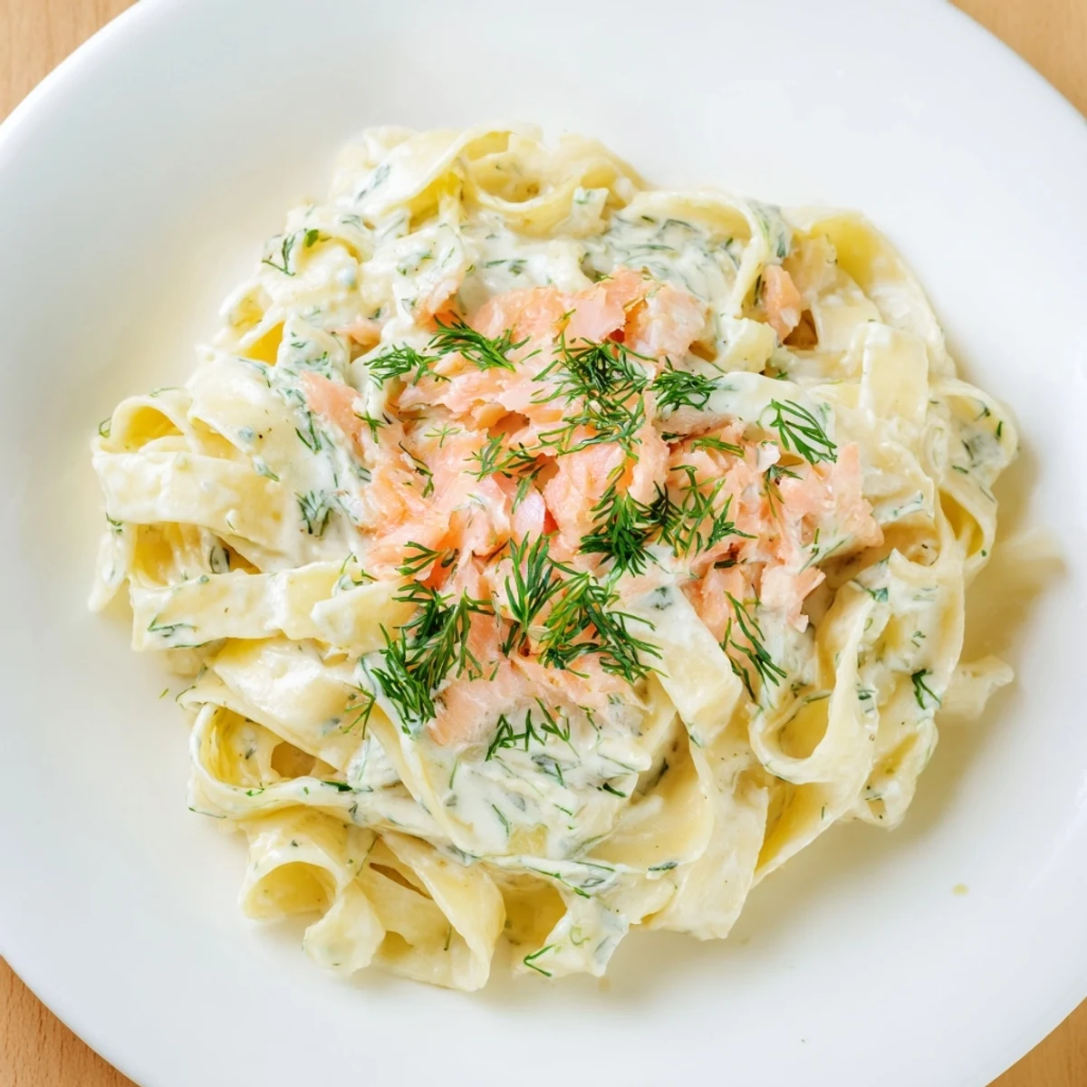 Creamy hot smoked salmon pasta topped with fresh dill in a white bowl.  