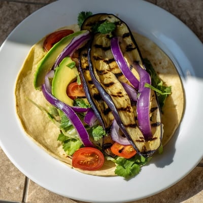 Savory grilled eggplant strips are layered into soft tortillas, garnished with cilantro and a squeeze of lime.