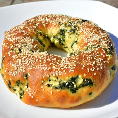 Freshly baked spinach cottage cheese flagels topped with sesame seeds, ready to be enjoyed with butter for breakfast.