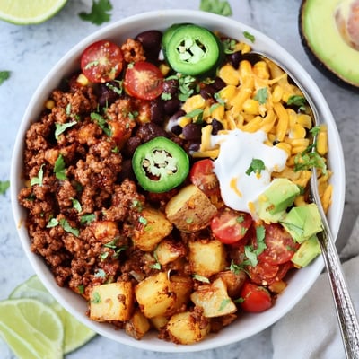 Warm Loaded Potato Taco Bowl piled high with seasoned beef and avocado