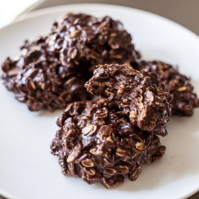 Glossy chocolate oatmeal no bake cookies with visible oats cooling on wax paper