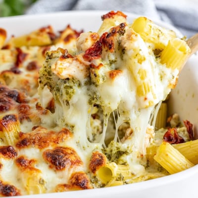 Creamy pesto chicken pasta bake scooped from a cast iron serving dish