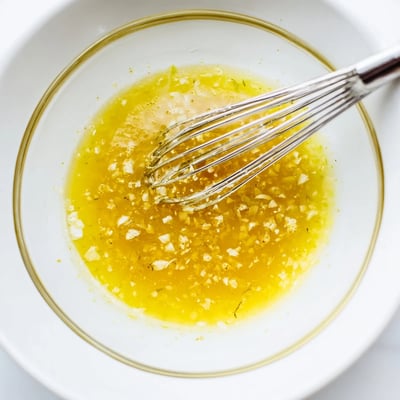 Golden olive oil emulsified in lemon vinaigrette dressing recipe drizzled over crisp greens.  